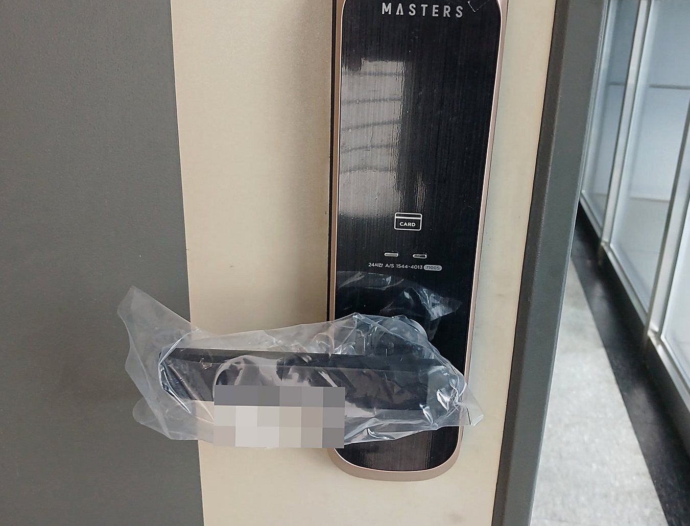덕양구 주교동 출장 — 회갈색 문에 달린 구릿빛 테의 검은 번호키와 비닐 씌운 레버 손잡이